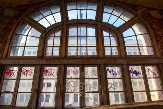 A Large and Detailed Arched Window in an Abandoned Building Covered in Graffiti