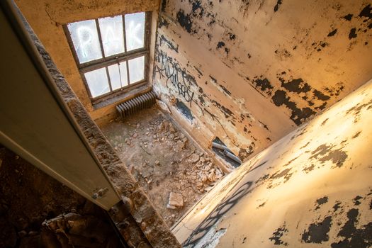Looking Down Into a Small Room in an Abandoned Building Covered in Debris and Graffiti