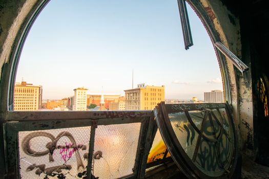 Looking Out a Large and Broken Arched Window at a City Skyline and Clear Sky in an Abandoned Building