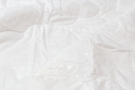 White fabric blanket with one big fold close-up backdrop with selective focus and background blur. Small white squares pattern.