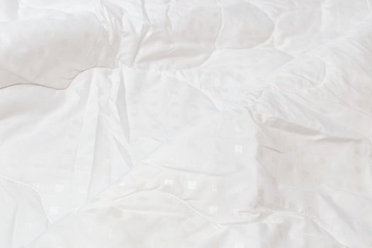 White fabric blanket with one big fold close-up backdrop with selective focus and background blur. Small white squares pattern.