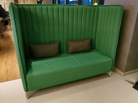 Green sofa with two small pillows in a hotel lobby
