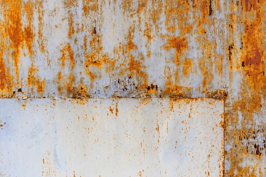 rusted flat sheet metal surface with leftovers of white and light blue paint, with rectangular patch in the corner.