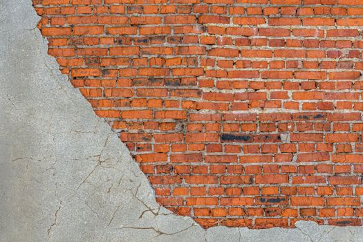 old bad brick wall with leftovers of gray peeled thick sandy plaster.