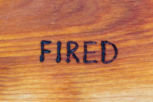 the word fired handwritten with hand woodburner on flat brown wood surface in flat lay directly above composition