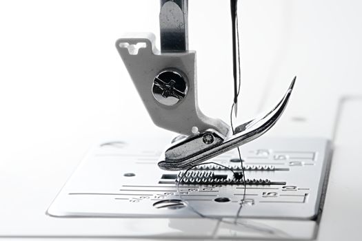 2 - Needle point and thread in macro side view of sewing machine feed dogs and throat plate.