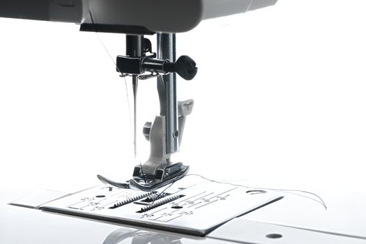 8 - Medium horizontal image of sewing machine working area. Plate foot needle thread and housing above is all visible.