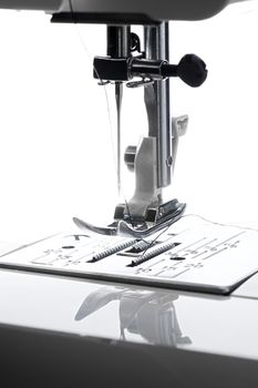 9 - Vertical close up macro image of bright needle and sewing machine working area.
