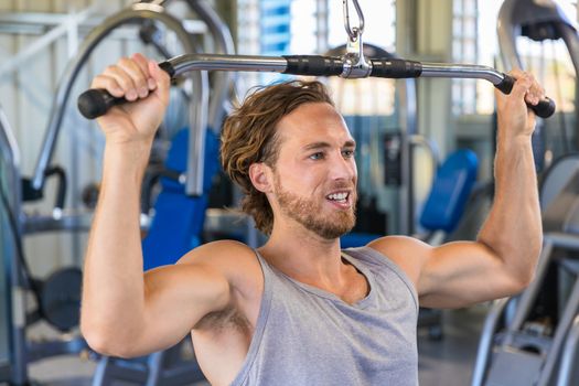 Shoulder pull down machine. Fitness man working out lat pulldown training at gym. Upper body strength exercise for the upper back.