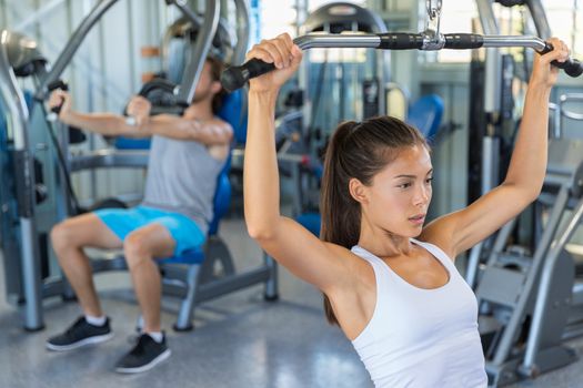 Fitness girl working out shoulders and upper back at lat pulldown machine, strength training at gym.