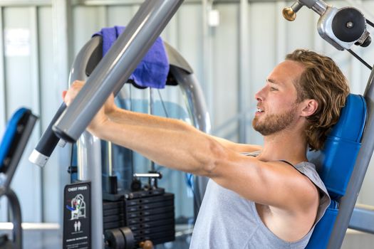 Man exercising at gym. Fitness athlete doing chest exercises on vertical bench press machine.