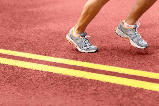 Man running on road. Low section of sporty male wearing sports shoes. Athletic runner is exercising by double yellow lines.