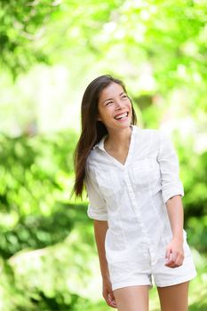 Cheerful young woman looking away while walking in park. Happy female is in casuals. Attractive female is laughing while spending leisure time during summer.