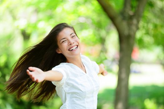 Cheerful young woman with arms outstretched enjoying in park. Portrait of beautiful female is in casuals. Joyful woman is enjoying nature during summer.