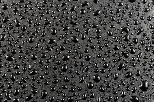 close-up view of water drops on black flat matte surface macro sith selective cous and background blur