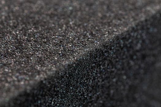 Close-up view of an edge of black rubber foam sponge brick. Selective focus with shallow depth of field.