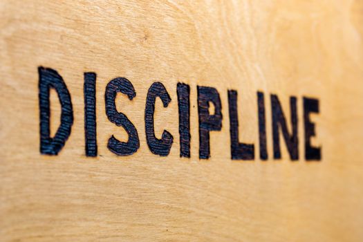 the word discipline burnt on white flat wooden surface - perspective view with selective focus and blur