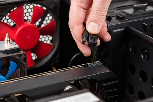 pc engineer hand holding 6 plus 2 pin video card power connector while maintenance.