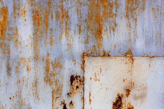 rusted flat solid sheet metal surface with leftovers of white and light blue paint, with rectangular patch in the corner.