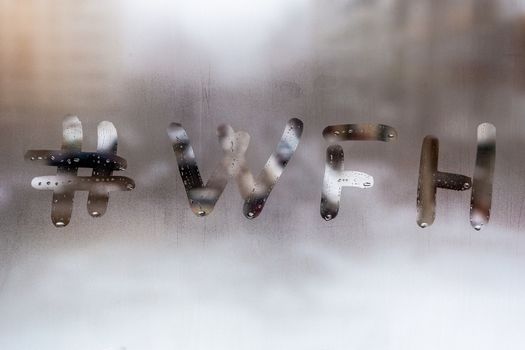 hashtag word wfh - work from home handritten on wet window glass at cloudy weather - close-up with selective focus and background blur