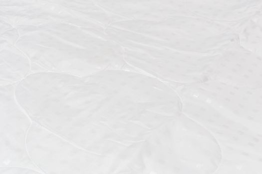 White fabric blanket close-up backdrop with selective focus and background blur. Small white squares pattern.