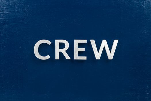 the word crew laid with brushed white metal letters over flat blue board - in center of picture, directly above perspective