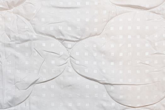 White fabric blanket close-up texture and background. Small white squares pattern.