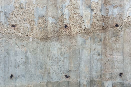 an outdoor thick rough gray concrete wall with visible imprints of wooden planks, twice filled