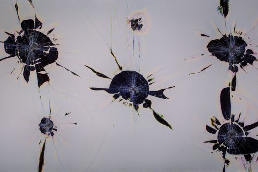 Close-up view of physically damaged lcd screen surface with multiple separated impact spots, radial cracks, pixel grid leakage and discoloration. Full frame background of dead monitor.