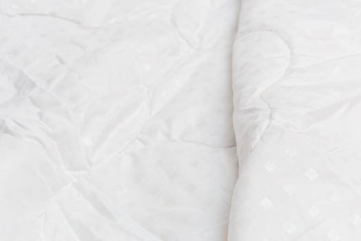 White fabric blanket close-up backdrop with selective focus and background blur. Small white squares pattern.