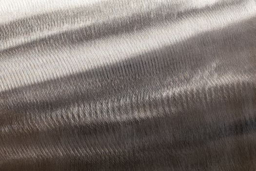 Close-up texture of flat steel surface manually cleaned with a flap wheel angle grinder. Surface prepaired before painting as part of the repair work.