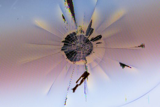 close-up view of physically damaged lcd screen surface with impact spot, radial cracks, pixel grid leakage and discoloration.