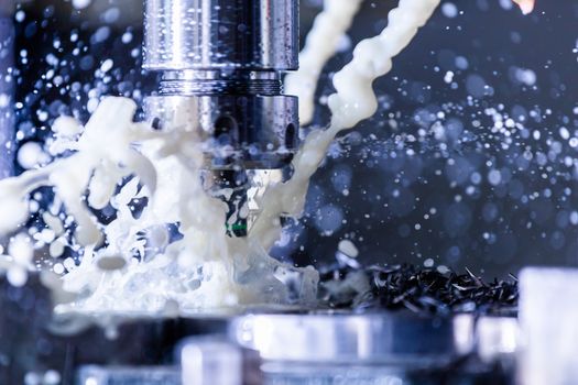 A process of vertical cnc steel milling with external water coolant streams, splashes and a lot of metal chips. Fast shutter speed for motion freezing.