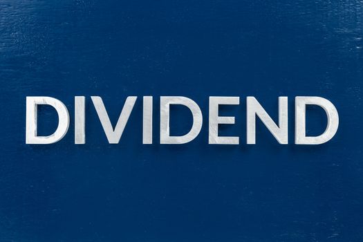 the word dividend laid with white brushed metal letters on dark blue background