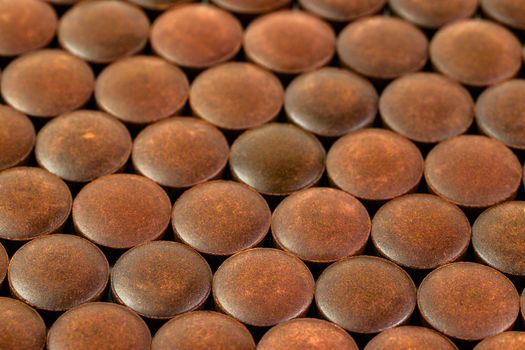 close-up background of many orange organic powder tablets laid tight in one layer on flat surface.