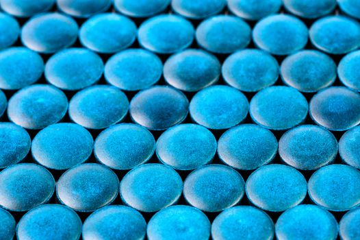 close-up background of many blue organic spirulina tablets laid tight in one layer on flat surface.