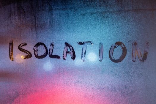 the words self isolation handwritten on wet window glass at night - close-up full frame picture with selective focus and background blur