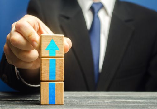 Businessman builds a tower of blocks with an up arrow. Career promotion , growth of professional skills. Business development, expansion improvement. Profit growth. Marketing. Improving efficiency
