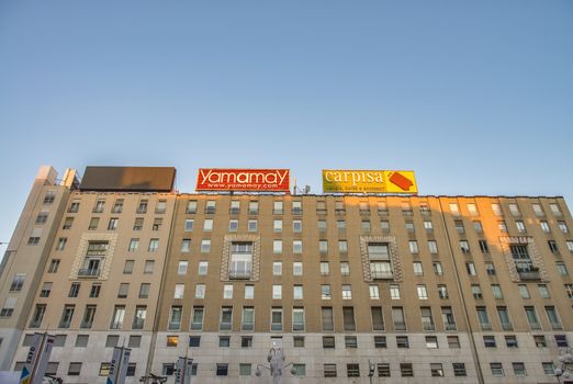 MILAN, ITALY - SEPTEMBER 2015: City buildings with advertisings at sunset.