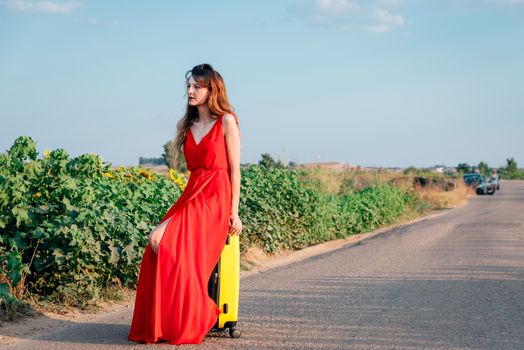 sad woman sitting in a suitcase on the road