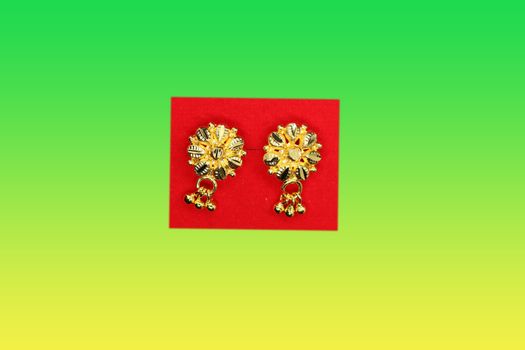 Beautiful shiny gold earring on red and gradient background