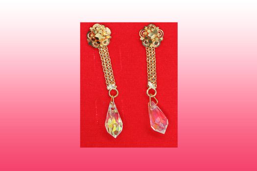 A pair of gold earrings in demand on gradient background