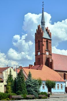 tenement houses on the market square and the tower of the historic gothic church in the village of Bledzew in Poland