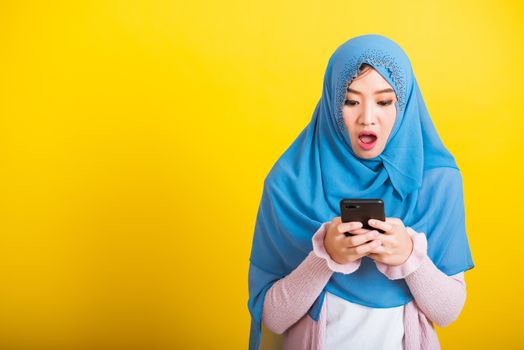 Asian Muslim Arab, Portrait of happy beautiful young woman Islam religious wear veil hijab funny smile she reads surprised confused shock news open mouth, studio shot isolated on yellow background