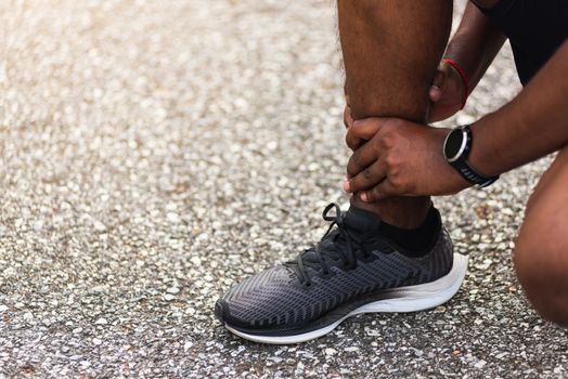 Close up Asian young sport runner black man wear watch hands joint hold leg pain because of twisted ankle broken while running at the outdoor street health park, healthy exercise Injury from workout