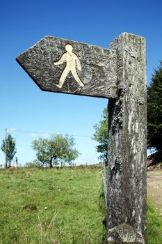 Wooden footpath arrow signpost with a blue sky directing walkers rambles and hikers stock photo