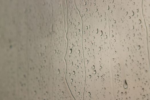 Water rain drops on window glass surface with cloudy background for your design. Natural Pattern of raindrops on glass background. Copy space, No focus, specifically.