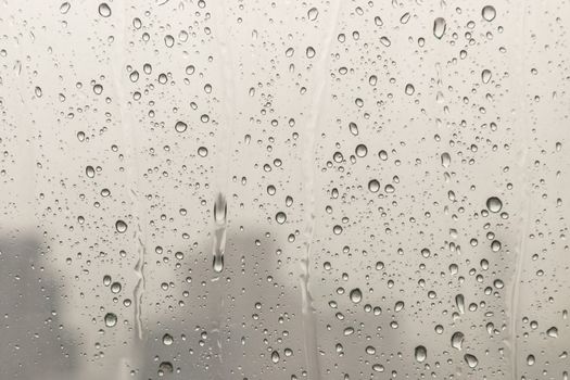 Water rain drops on window glass surface with cloudy background for your design. Natural Pattern of raindrops on glass background. Copy space, No focus, specifically.