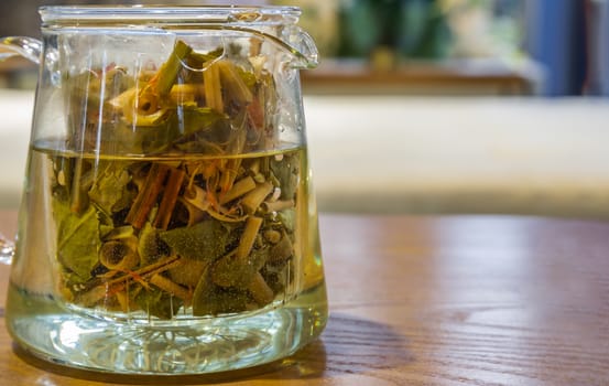 Fresh organic herbal tea in teapot in the room background. selective focus.