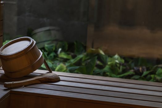 Detail of wooden bucket in a sauna on natural background. Relaxation concept. Selective focus.